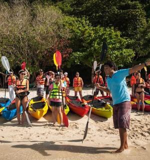 a group of people standing on a beach with kayaks