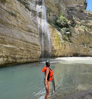 a man standing in the water in front of a waterfall