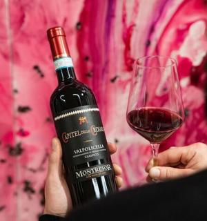 a person holding a bottle of wine and a glass