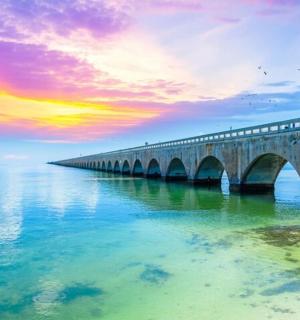 a bridge over the water with a sunset in the background