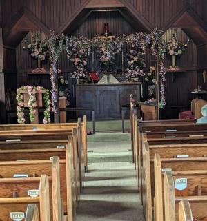 一座空荡荡的教堂，有木制长椅，祭坛上有一位牧师