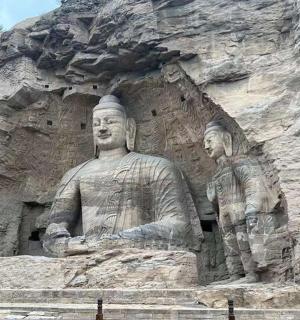 socha dvou mužů sedících na skalní stěně