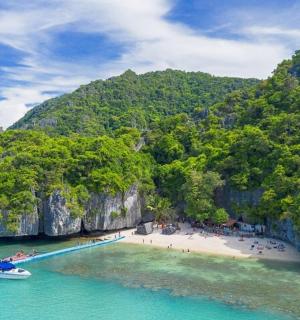 a beach with a boat in the water next to cliffs