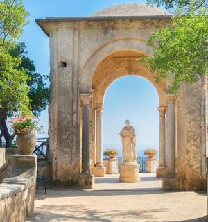 an archway with a statue in front of the water