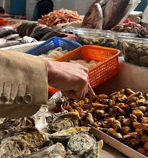 一个人在市场上伸手去拿一盘海鲜