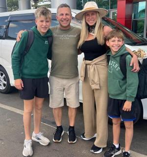 a man and a woman and two children standing next to a van