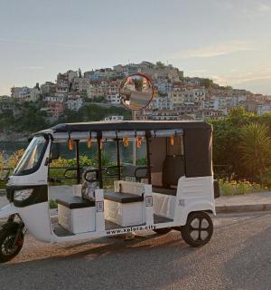 a small vehicle driving down a road with a city