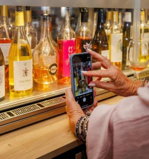 一位女士正在给一瓶葡萄酒拍照