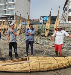a group of people standing around a boat on the beach