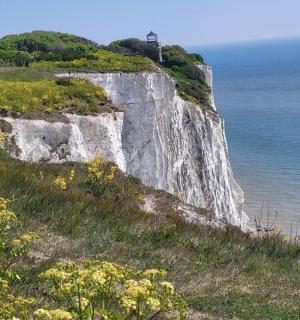 a white cliff with a lighthouse on it next to the ocean