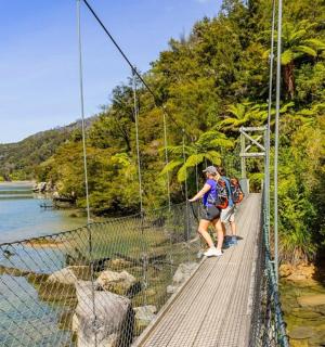 muž kráčející po visutém mostě nad řekou