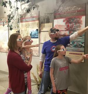 a group of people wearing glasses looking at a poster