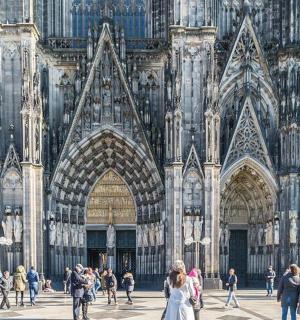 a group of people walking in front of a cathedral