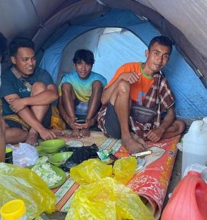 three men sitting in the front of a tent