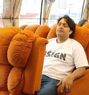 一名男子坐在公交车上的橙色座位上