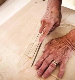 a person using a knife to cut a piece of wood