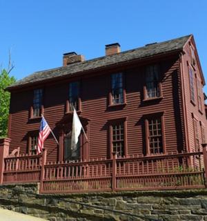 Starý dřevěný dům s americkou vlajkou na plotě