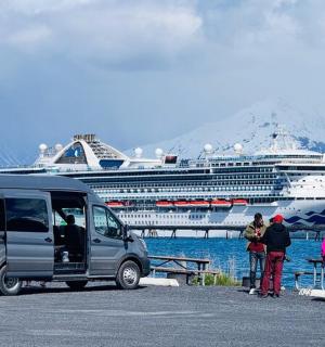 a van parked in a parking lot with a cruise ship
