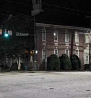 an intersection at night with a large brick building