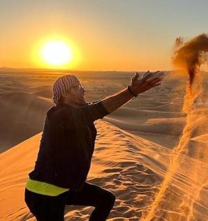 muž v poušti ukazující na západ slunce