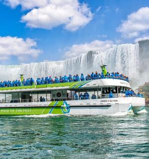 a tour boat in front of a waterfall