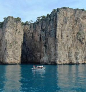 a boat in the water next to a large cliff