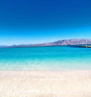 a beach with blue water and mountains in the background