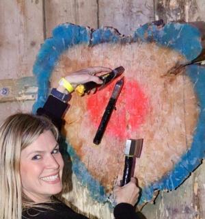 a woman is painting a heart on a wall