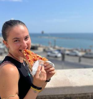 žena jí velký kus pizzy