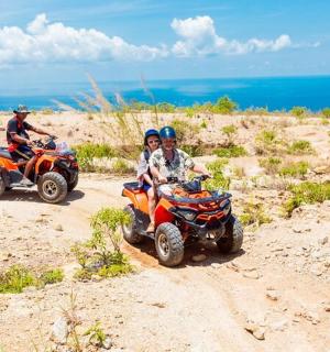 two people riding on atvs on a dirt road