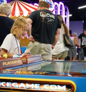 mladá dívka stojící vedle herní konzole