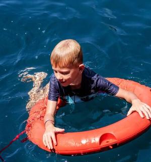 a young boy in the water in an orange raft