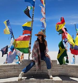 a woman is sitting on a wall with flags