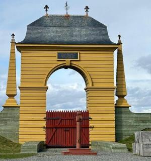 an arch with a red gate in front of a building