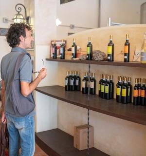 muž stojící před vystavenými lahvemi vína