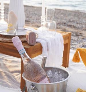 a bottle of champagne in a bucket on the beach