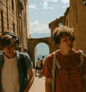 two young men walking down a street with headphones on