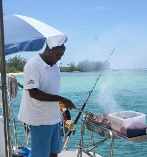 a man cooking food on a grill on a boat