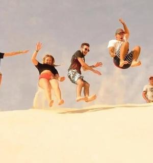 a group of people jumping in the sand