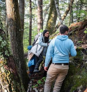 a group of people walking on a trail in the woods