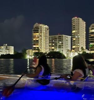 three people in kayaks on the water at night