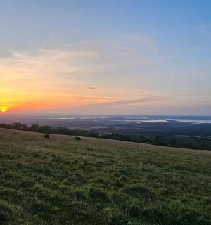 a sunset on top of a hill with a field