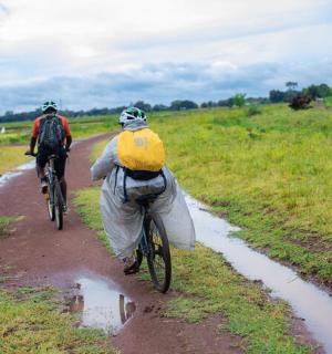 two people riding bikes down a dirt road