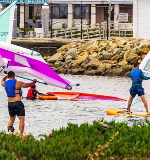 a group of people on the water with sailboards