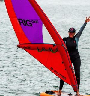 a man standing on a surfboard with a sail