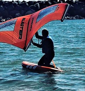 a man on a surfboard with a sail on the water