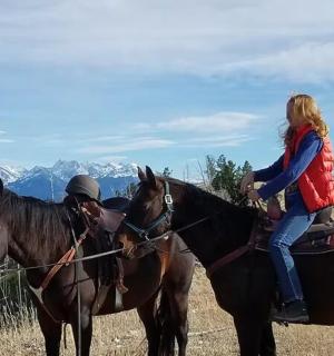 a woman riding on the back of two horses