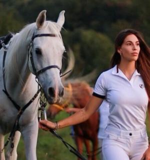 žena kráčející na bílém koni v poli