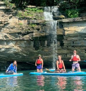 a group of people on paddle boards in the water near a waterfall