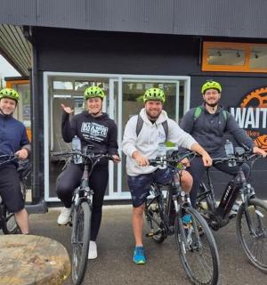 skupina mužů na kolech před budovou